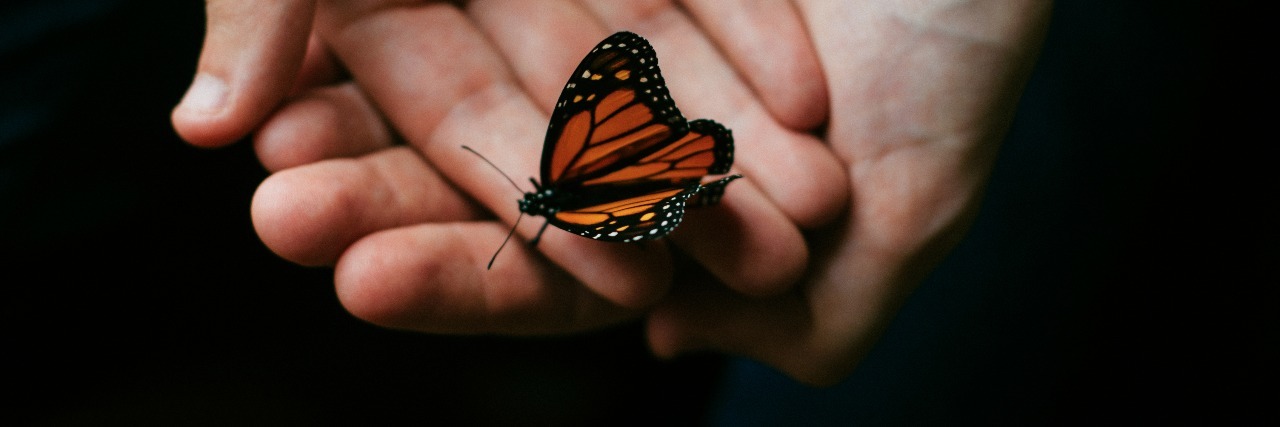 Anxiety: Poetry on What Anxiety Really Is woman's hands holding butterfly with dark background