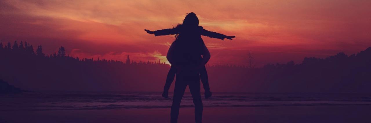 How Writing About Mental Health Has Changed My Life two people standing in water at sunset with one on the other's shoulders, arms spread wide