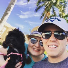 brother and sister holding a dog and standing under a palm tree