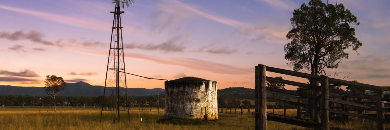 We Need More Support for Coping With Grief in Rural Communities Rural landscape. A fence, a windmill and a silo.