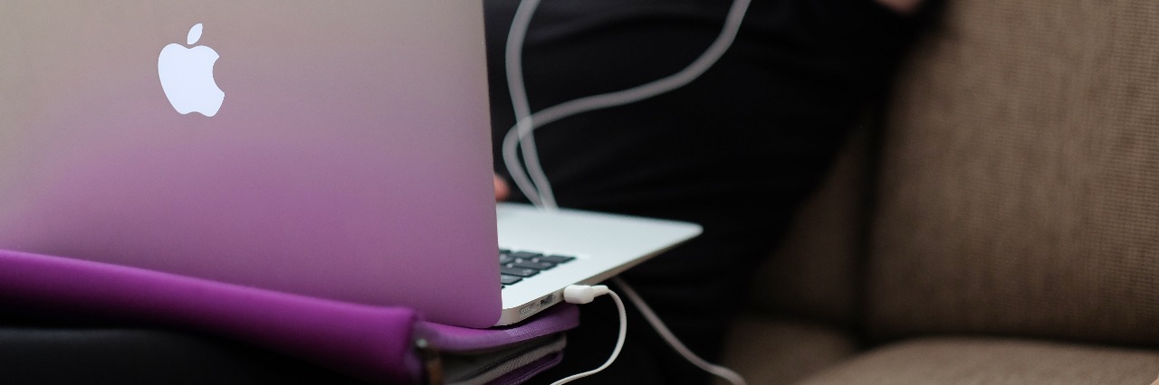 Why Saying You Can 'Beat' or 'Overcome' Anxiety Is Wrong woman reading or watching something on macbook laptop with phone by her side