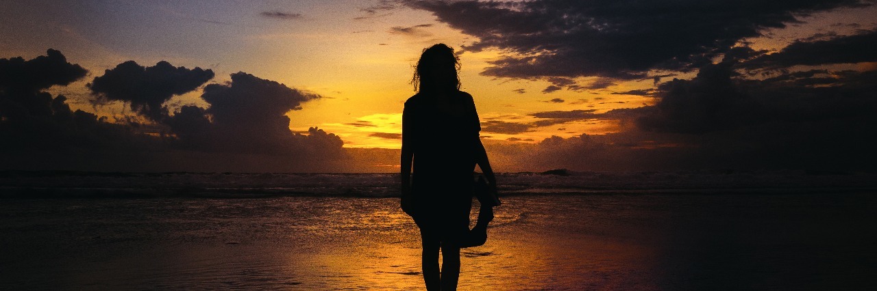 woman silhouetted before sunset standing in water