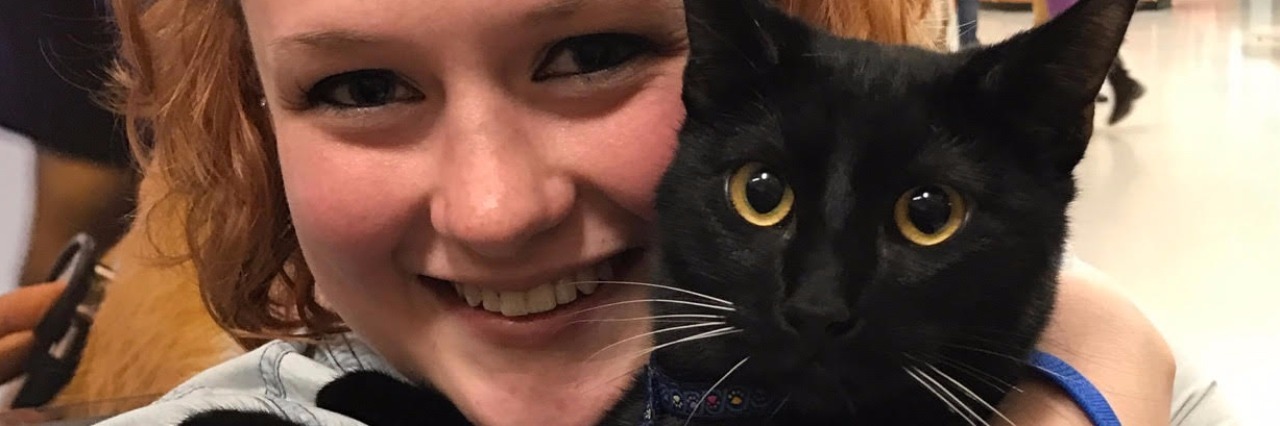 contributor smiling while holding emotional support animal black cat