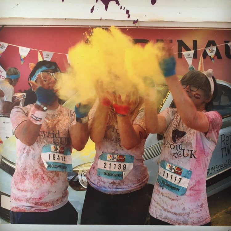 three women throwing yellow powder after completing a 5k color run