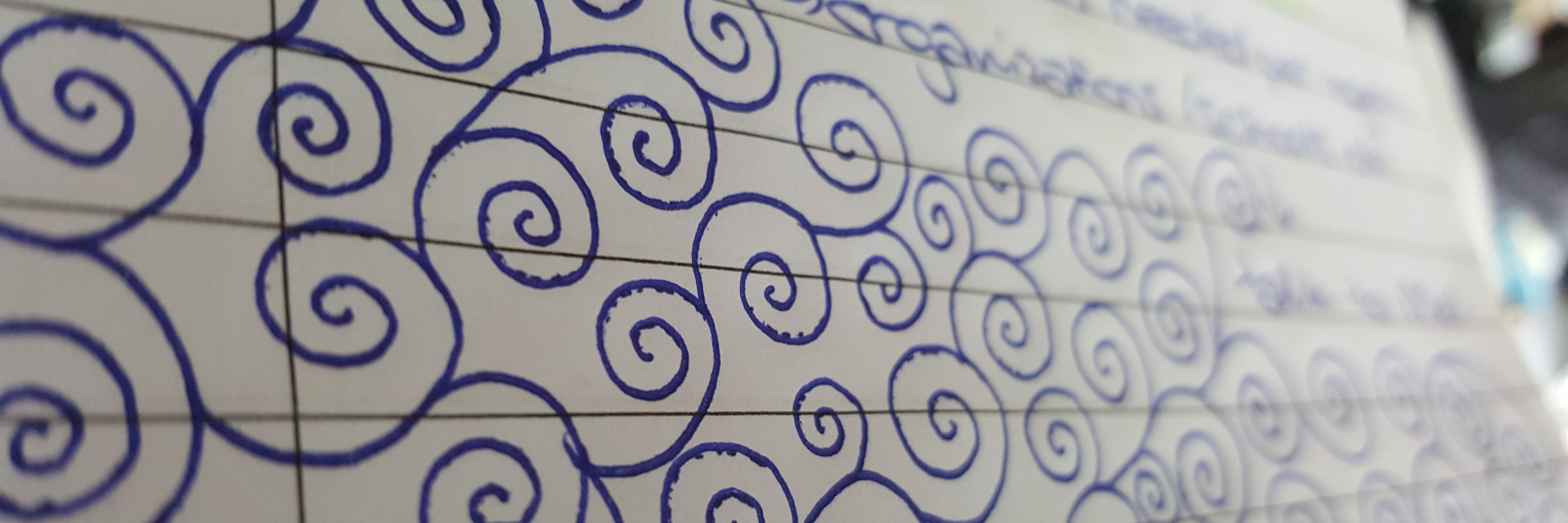 spiral doodles in blue pen in lined notebook