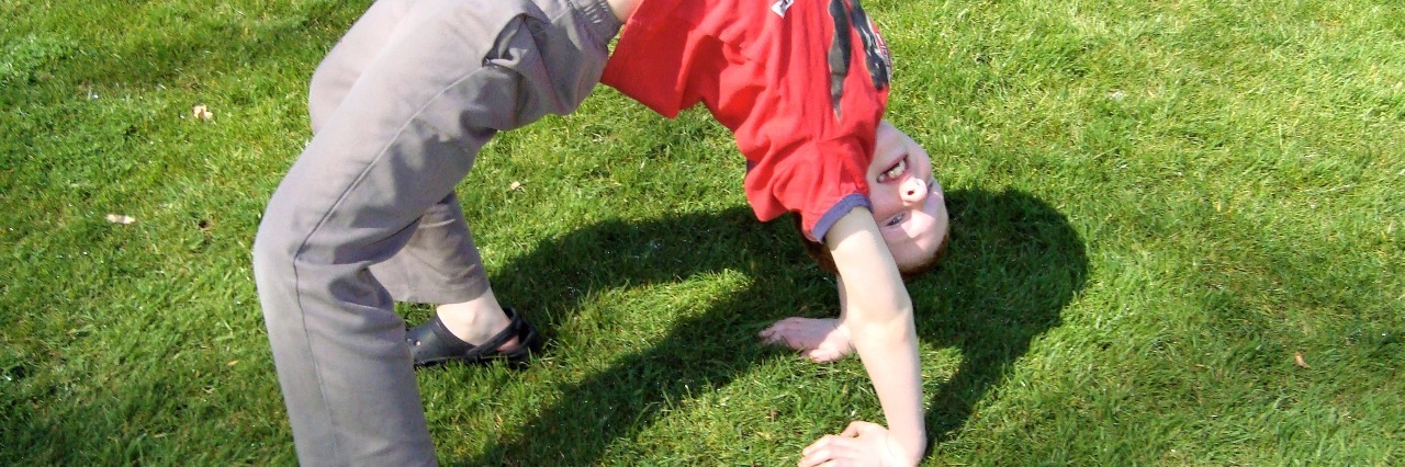 young boy doing a backbend outside