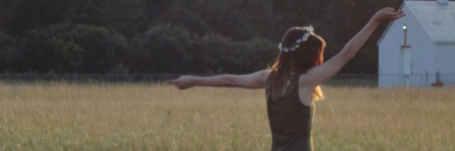 woman raising arms in field