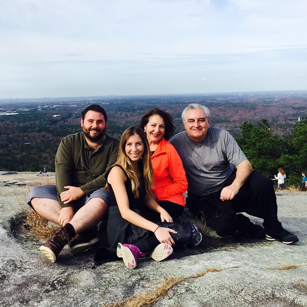 family sitting on the top of a mountain after a hike