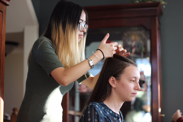 woman braiding a girl's hair