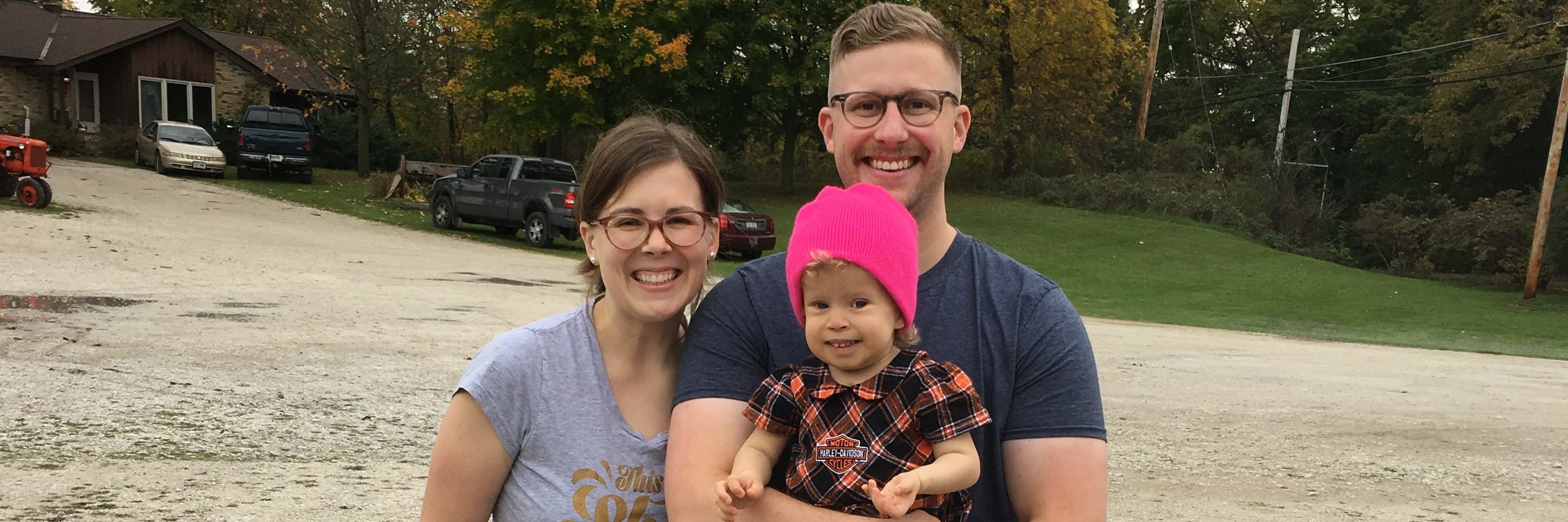 Talking About Healthcare Bill as a Parent of a Medically Complex Child parents holding their young daughter outside