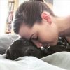 image of young woman resting head lovingly on black labrador dog