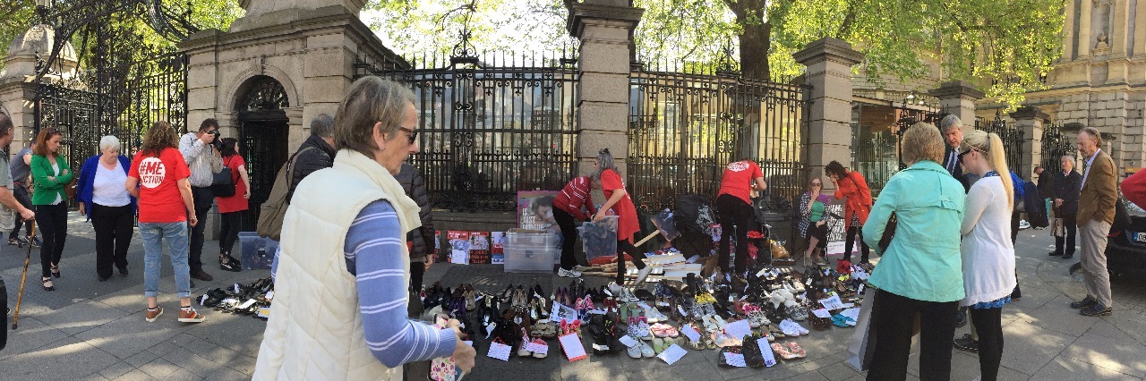 rows of shoes on ground in front of government building gate