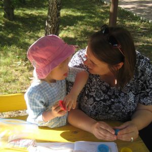 Lilya, a little girl wearing a yellow shirt and smiling.