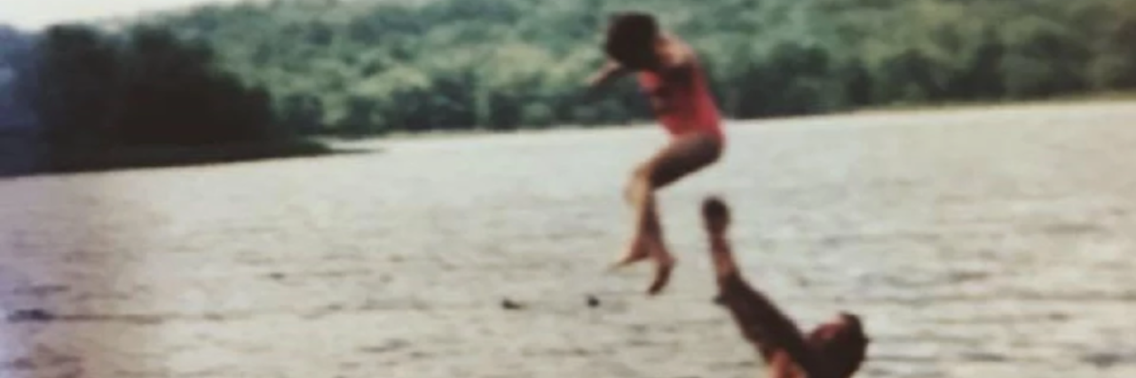 old picture of a dad throwing his daughter in the air while swimming in a lake