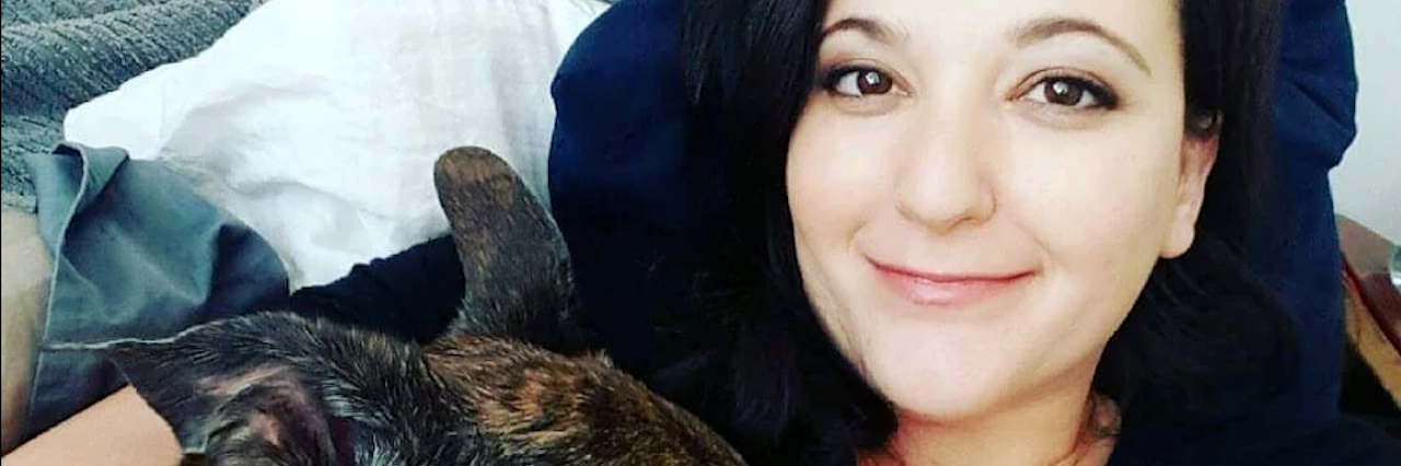 Accepting Life With Chronic Inflammatory Response Syndrome (CIRS) woman smiling and lying in bed with her dog