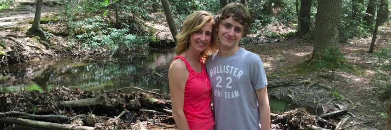 Mom and son standing together in forest setting