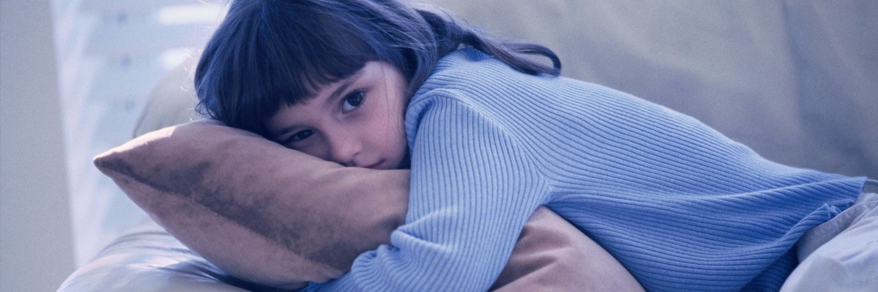 What It's Like To Be a Kid With Ehlers-Danlos Syndrome young girl hugging cushoin on the sofa