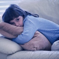 young girl hugging cushoin on the sofa