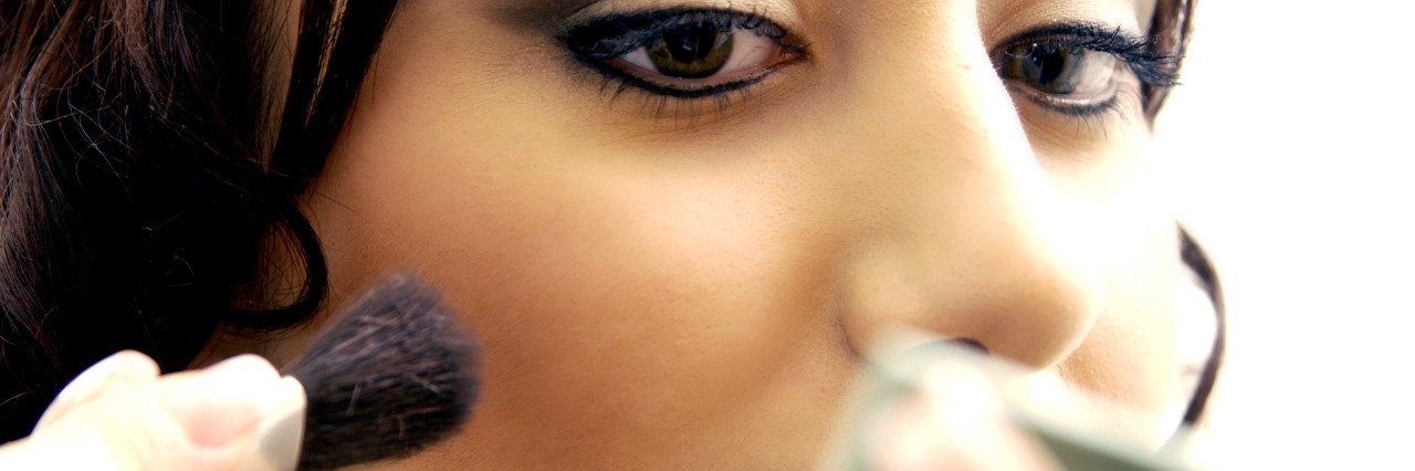 Endometriosis: Not Looking Sick Because of Invisible Illness woman applying makeup using compact mirror