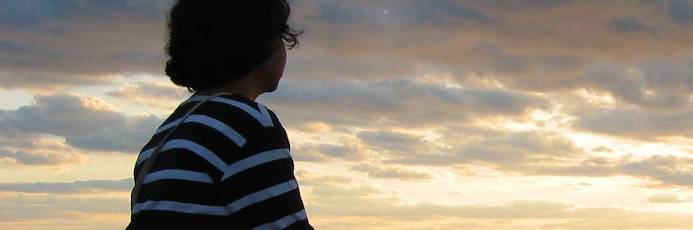 Acknowledging and Mourning the Loss of Miscarriage Woman sitting, looking at sea landscape with dark clouds in sky