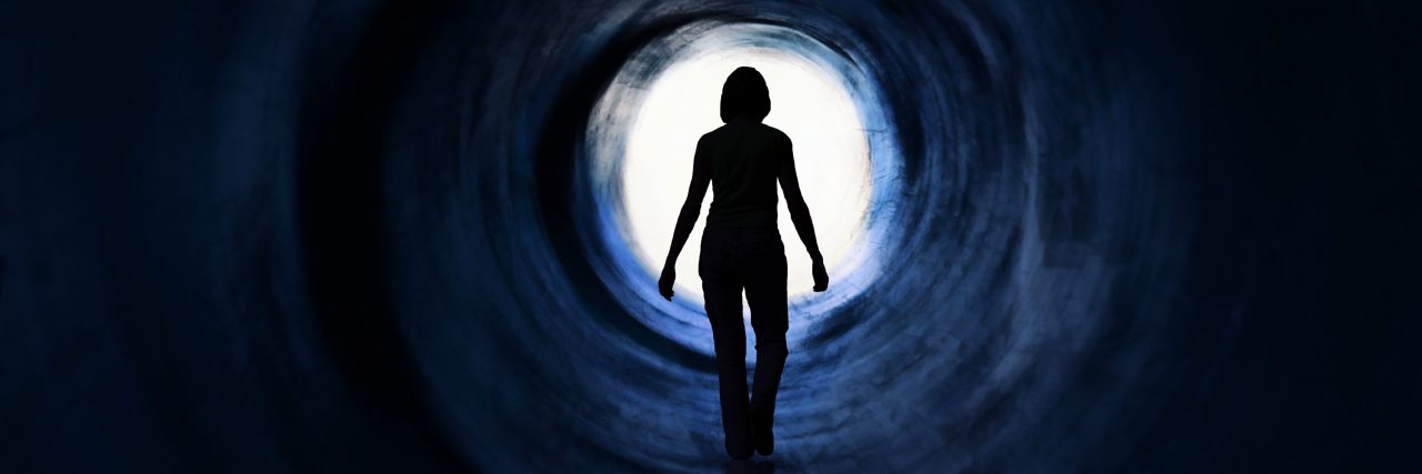 I Gave My Disease Six Months to Improve. It Didn't. Woman walking towards the light at the end of the tunnel