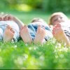 Group of happy children lying on green grass.