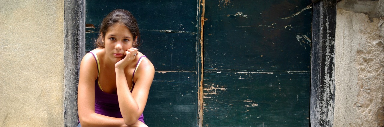 The Toll of a Chronic Illness Young girl sitting on steps at home
