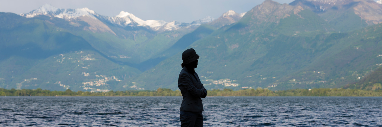 Living With Scoliosis and Standing Proud Woman standing up in a flooding alpine lake.