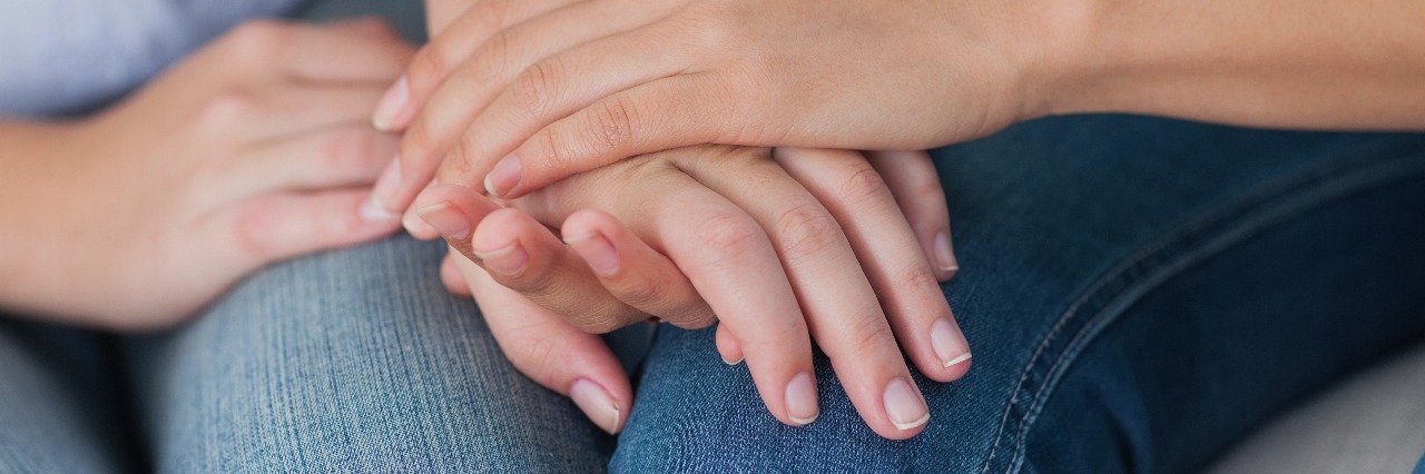 two people touching hands sitting close to one another