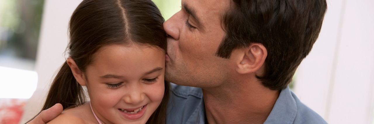 father kissing daughter on her forehead
