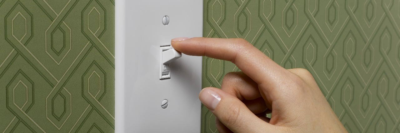 woman with finger to light switch and green wallpaper