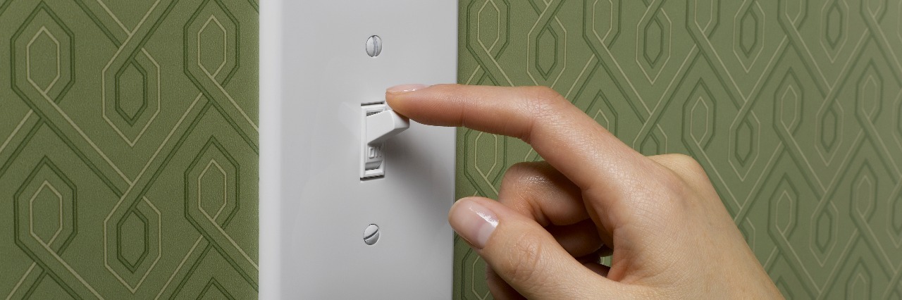 When Anxiety Is Unpredictable and Switches Between Extremes woman with finger to light switch and green wallpaper