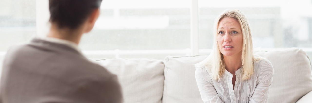 blonde woman talking to male therapist on sofa