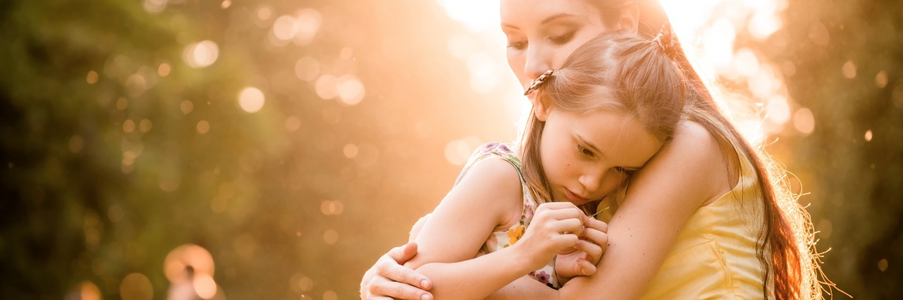 How I Received My Postpartum OCD Diagnosis mother cuddling daughter outdoors in nature