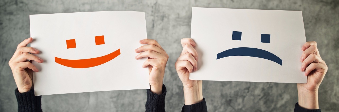 How Chronic Illness Has Affected My Positivity Two people holding up happy and sad faces.