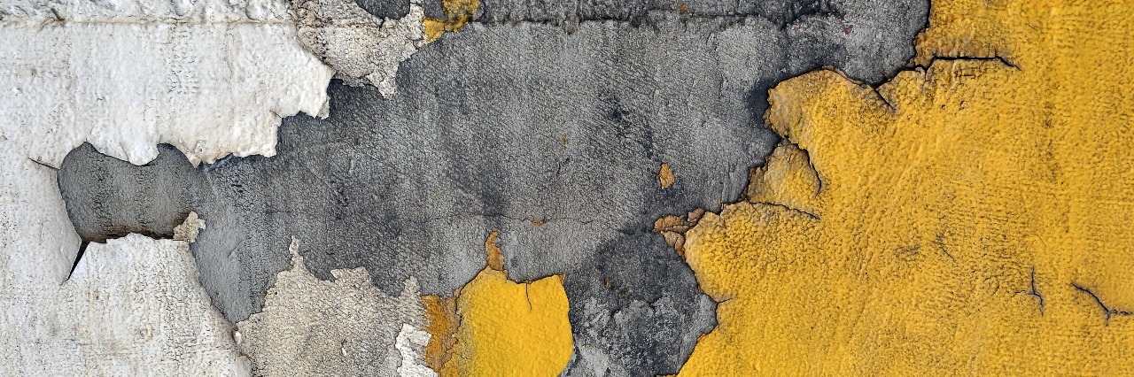 yellow paint chipping away from urban wall