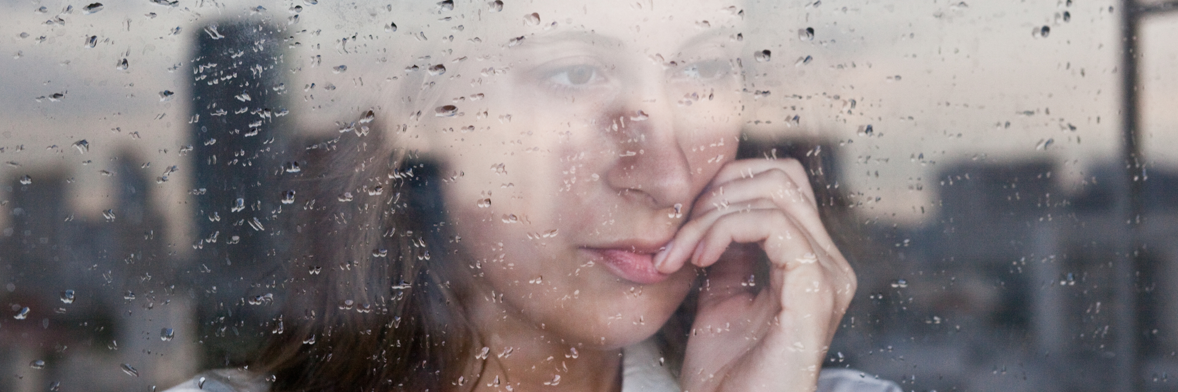 anxious woman looking out of window biting nails