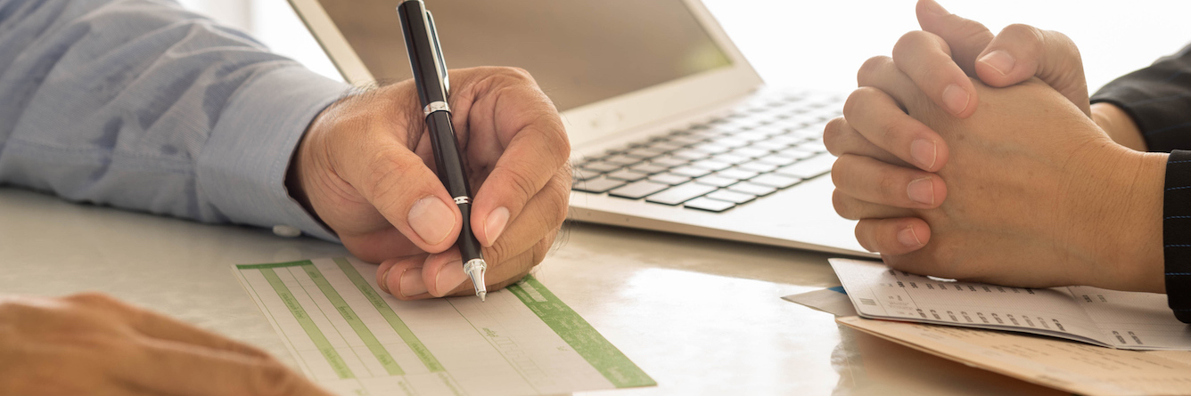 A Bank Employee Treated Me Differently After Learning I'm Autistic Bank employee and customer sitting at desk, bank employee filling out paperwork