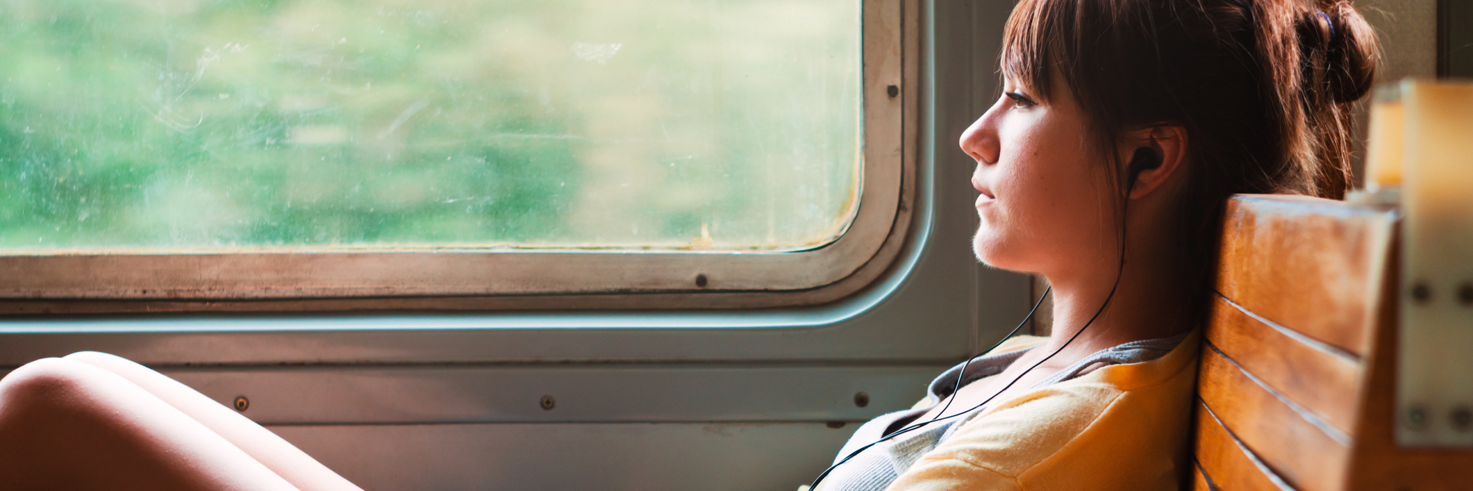 sad or contemplative girl on train listening to music on headphones