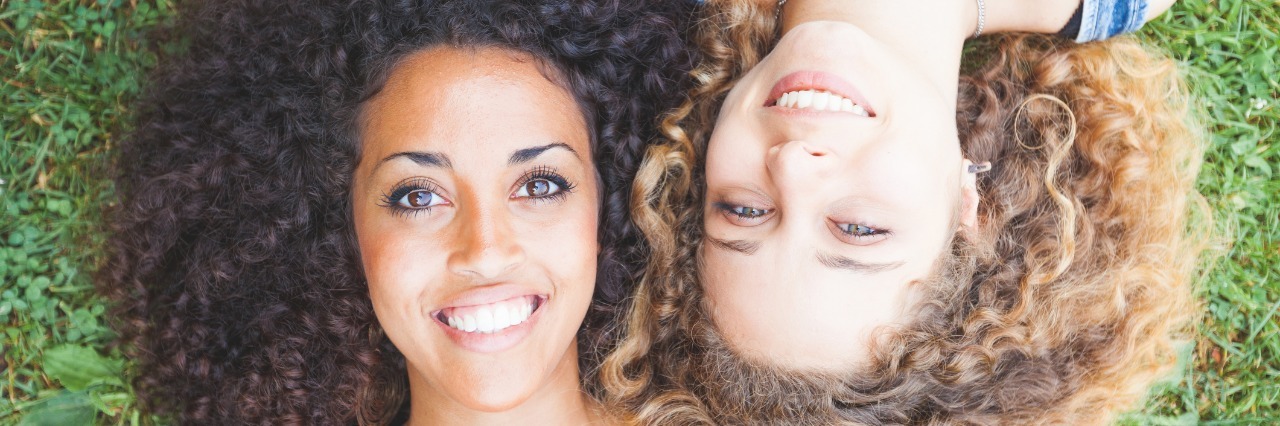 How to Support Your Friend With Chronic Illness two friends lying in the grass and smiling