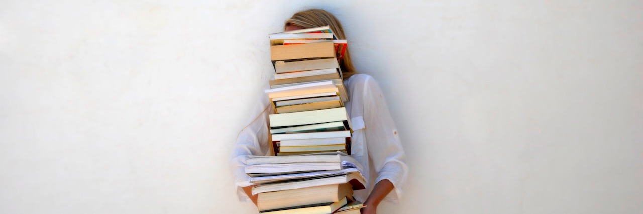 A woman holding a stack of books
