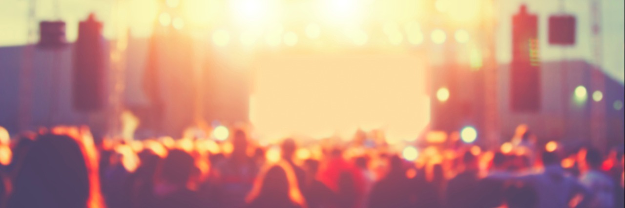 Music Festival Anxiety: 20 Tips to Get You Through Concerts A concert crowd stands before an outdoor sunlit stage for a music festival.
