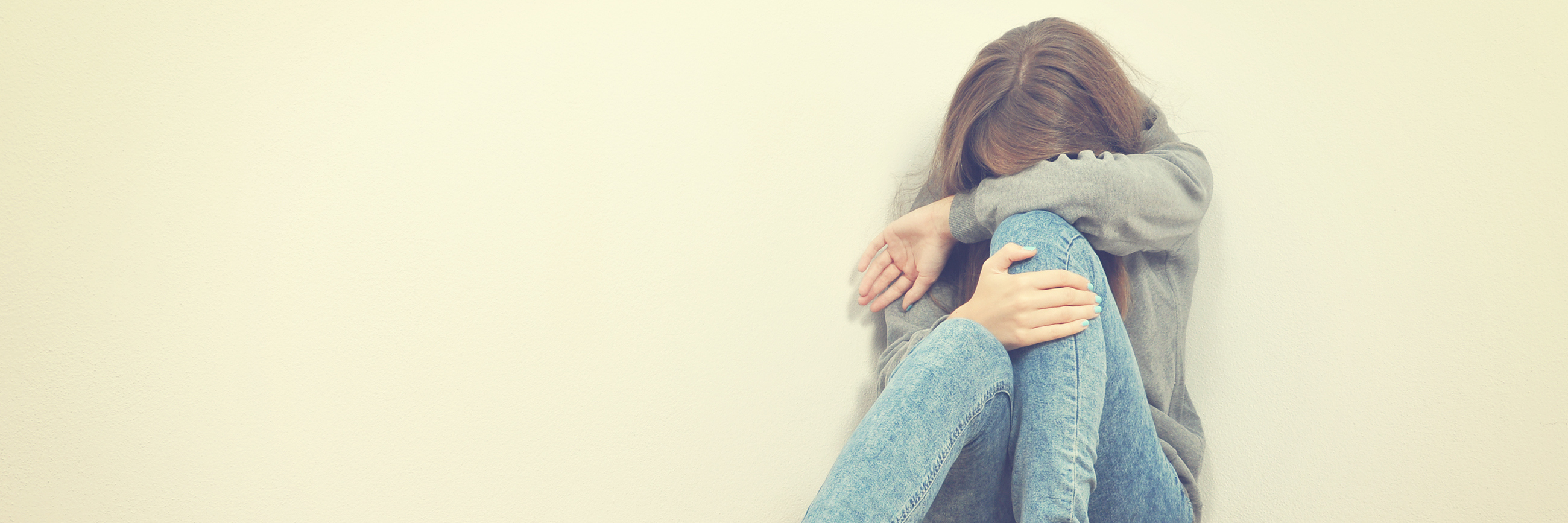 unhappy teen girl sitting in corner hugging knees