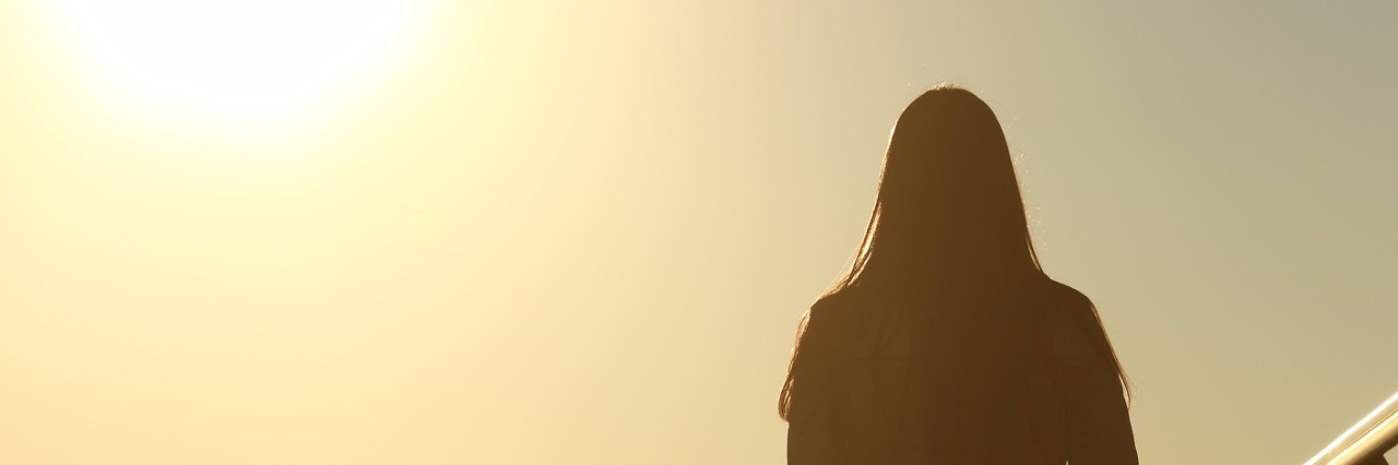 Sad woman silhouette walking alone at sunset