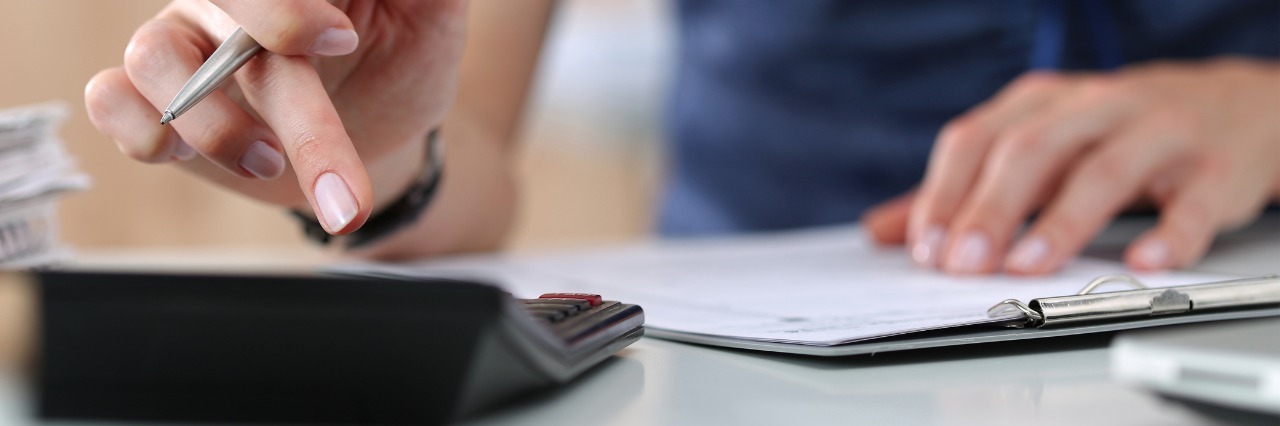 Defining Fibromyalgia: The Bank Account Analogy Close up of female accountant or banker making calculations.