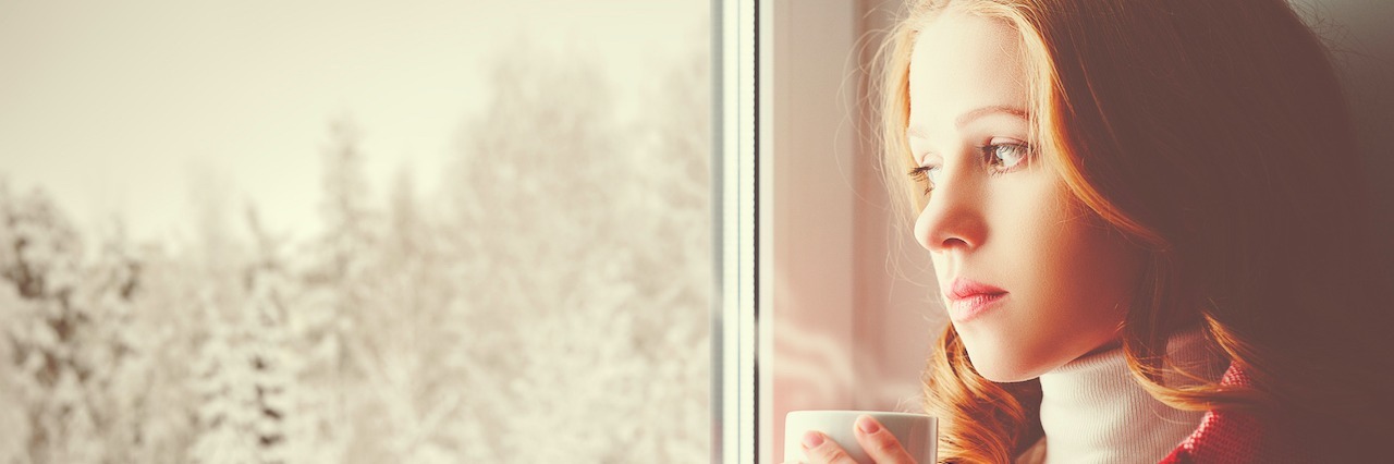 To the Person Dealing With Depression, From Someone Who’s Been There A woman drinking a cup of tea and staring out a window