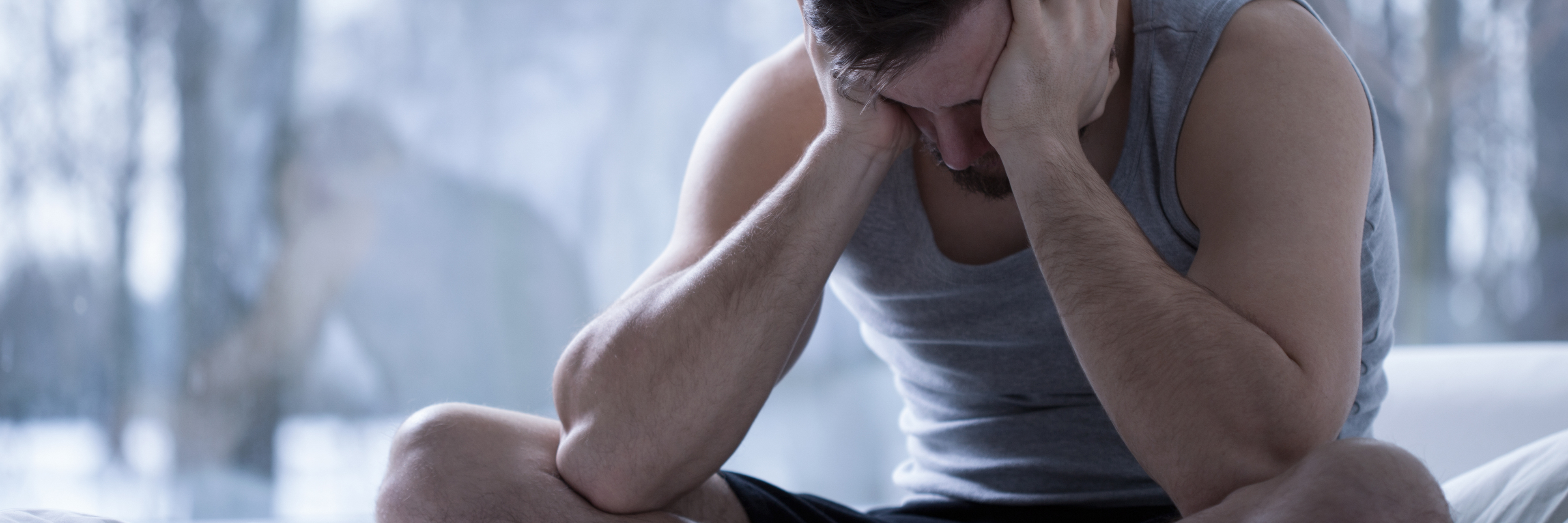 What Merit Badges for PTSD Would Look Like man with depression with head in hands sitting cross legged on bed