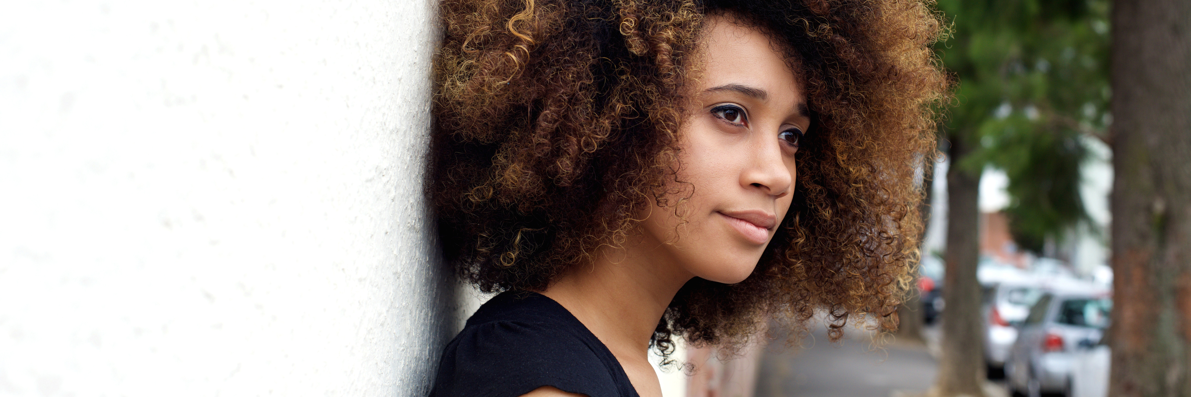 How Being Mixed-Race Affected My Body Image and Eating Disorder Side portrait of young african american woman leaning against wall and looking away