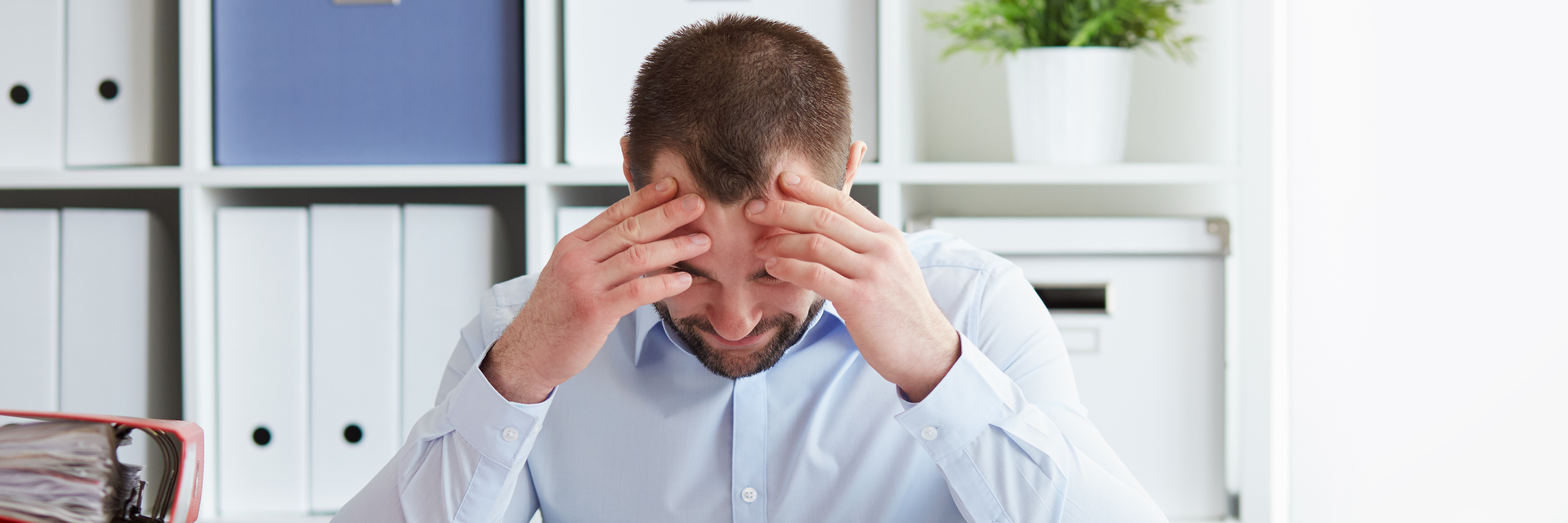 young businessman in office with anxiety or stress holding head