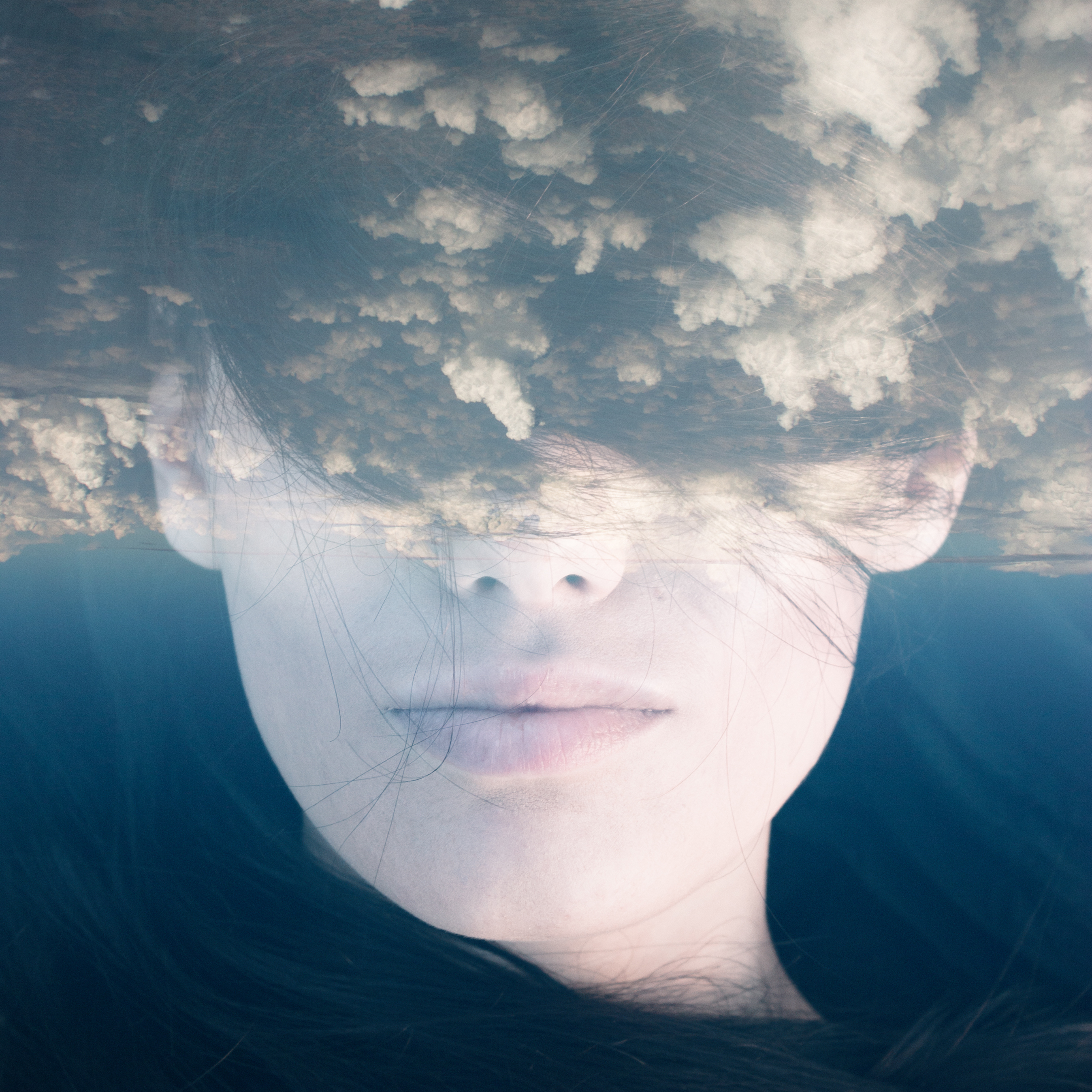 woman's face with double exposure of clouds covering her eyes